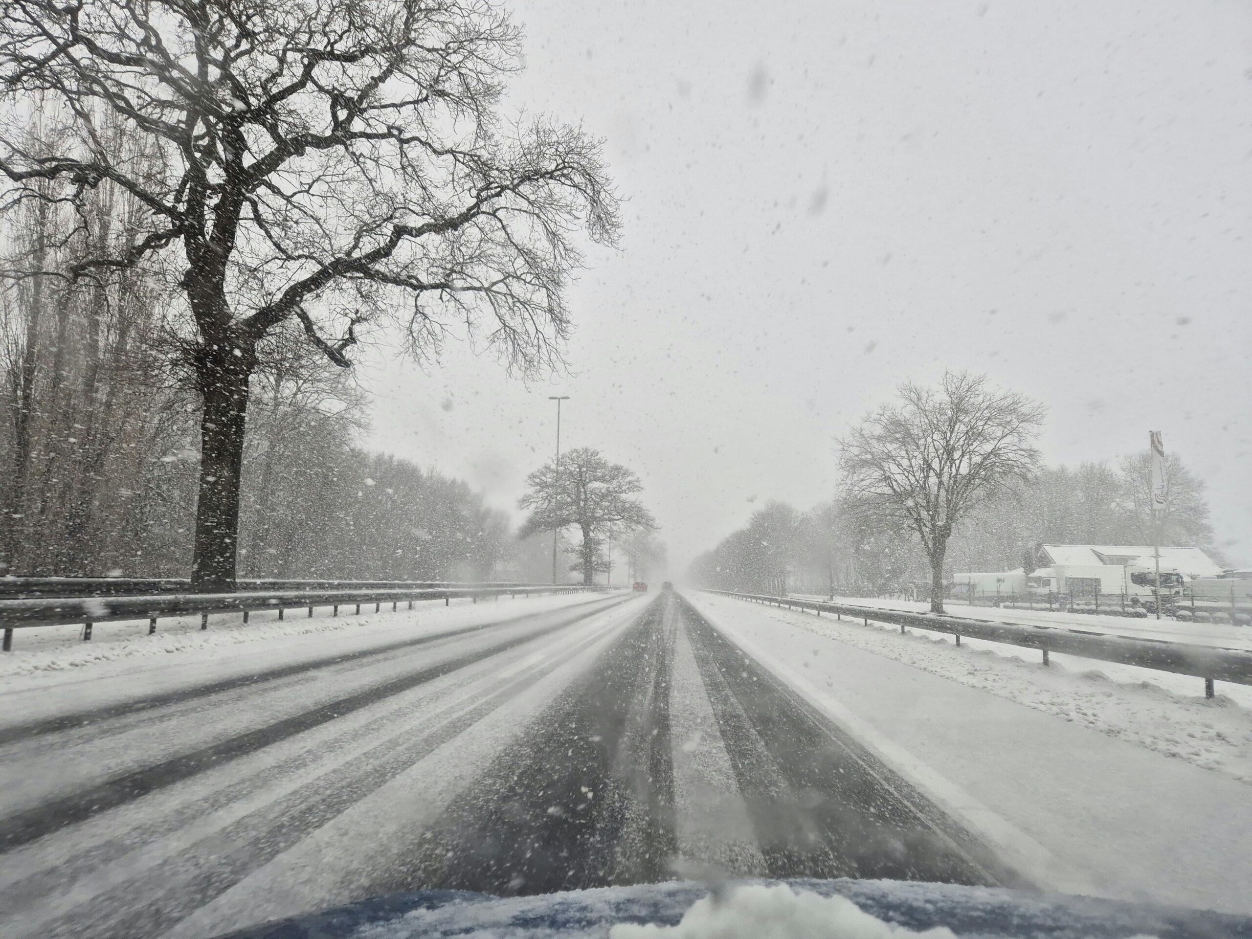 Gevolgen strooizout Nederland zichtbaar op besneeuwde wegen met zoutresten, schade aan asfalt en zoute bermen.